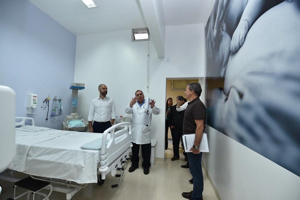 #PraCegoVer: secretário Edson Aparecido e o prefeito Bruno Covas recebem orientações sobre as salas de parto humanizado que serão  disponibilizadas à população. Na sala, há uma cama e equipamentos médicos para as gestantes e uma foto se uma mulher segurando carinhosamente um bebê na parede. 